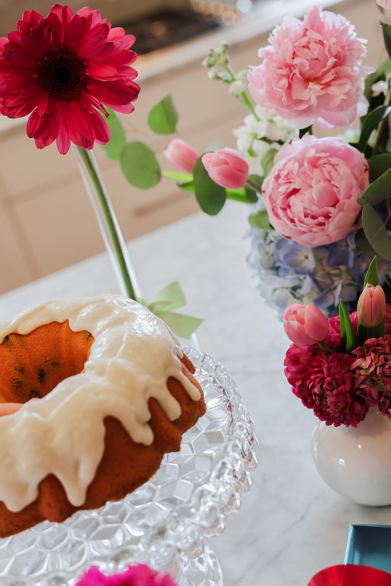 pound cake with white icing on a pedestal, various flowers in a kitchen in Tuscaloosa, Alabama