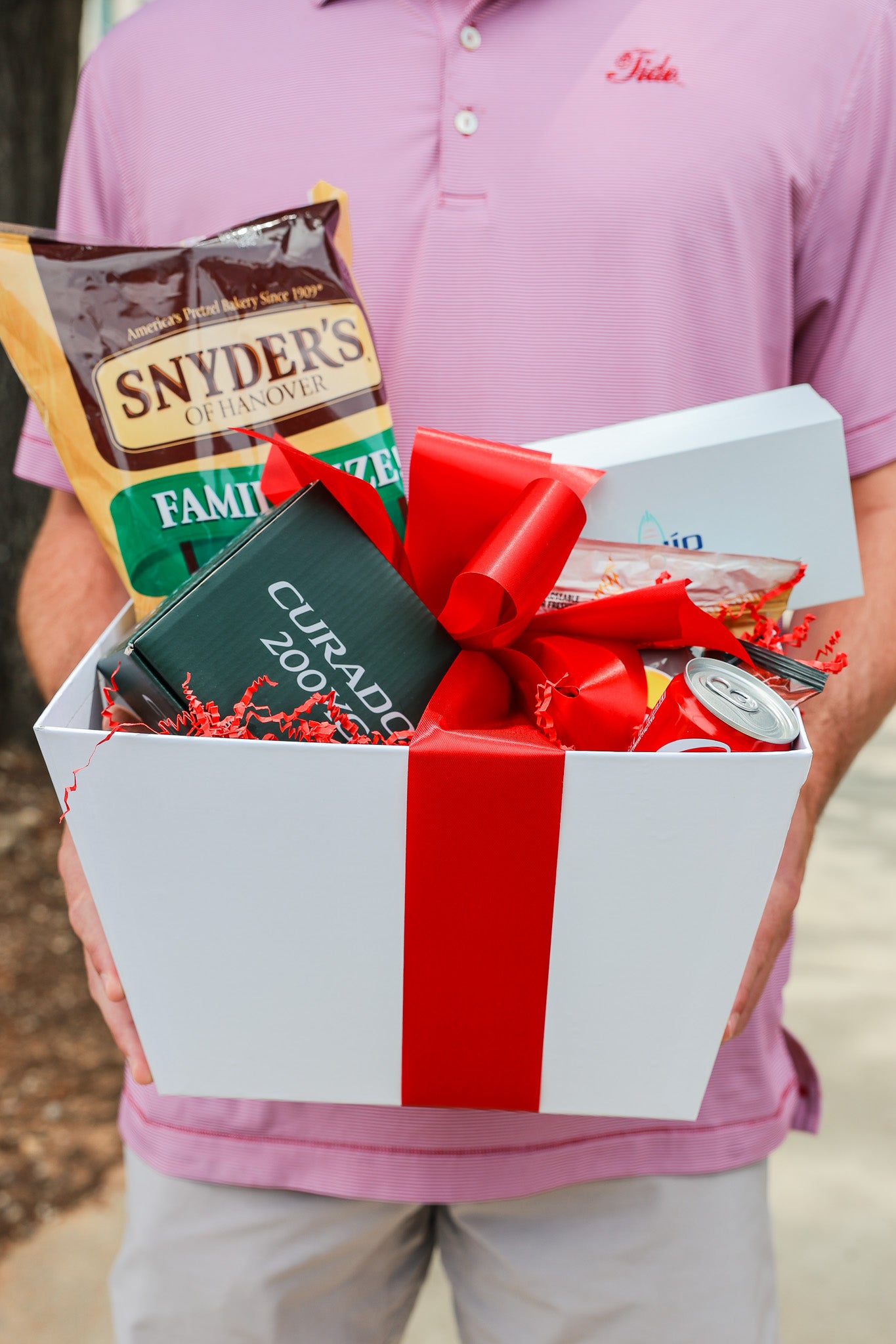 Boy holding gift basket wrapped with a red bow outside of University of Alabama's campus