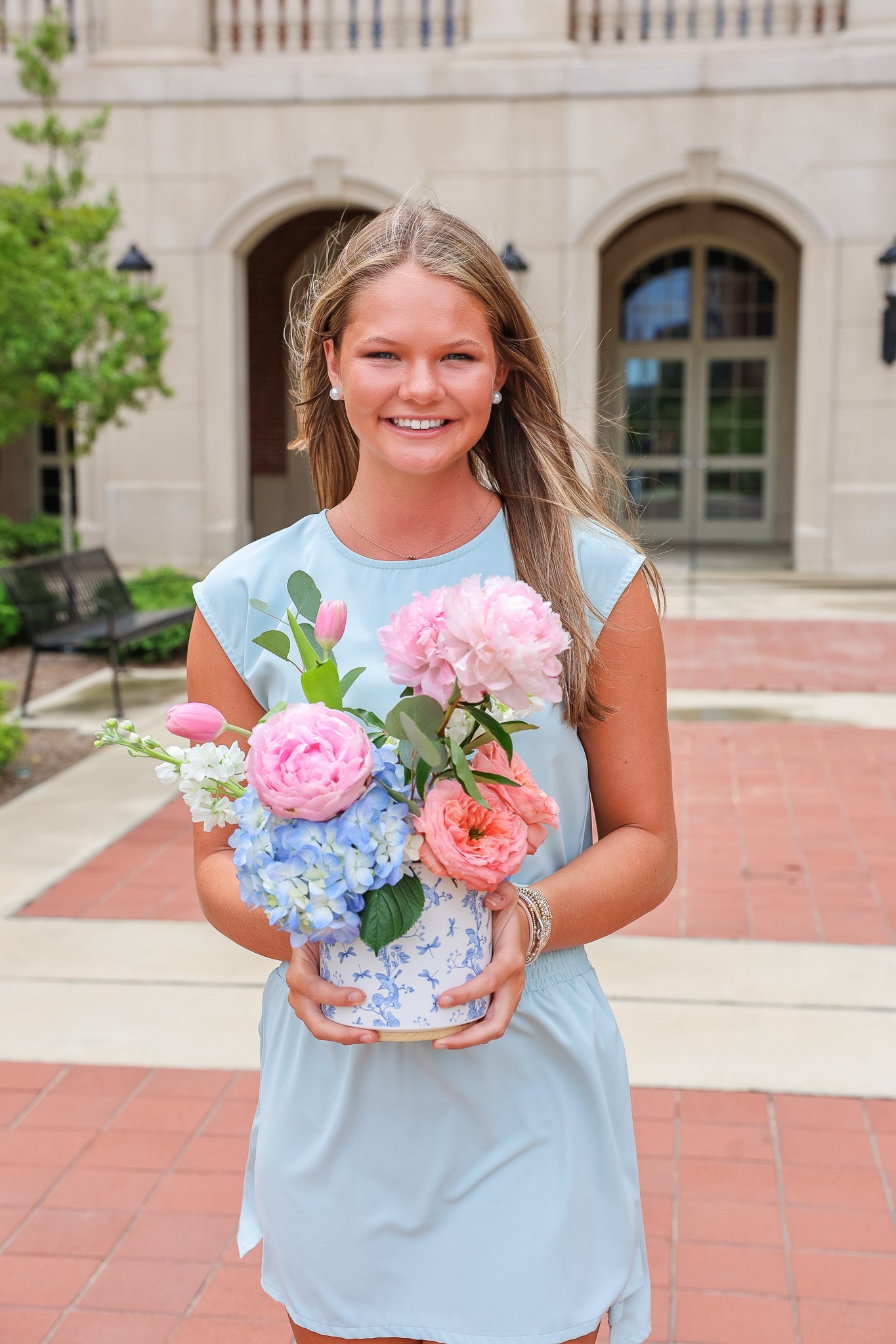 Photo of Taylor holding flower arrangement outside of Tutwiler Hall on University of Alabama campus