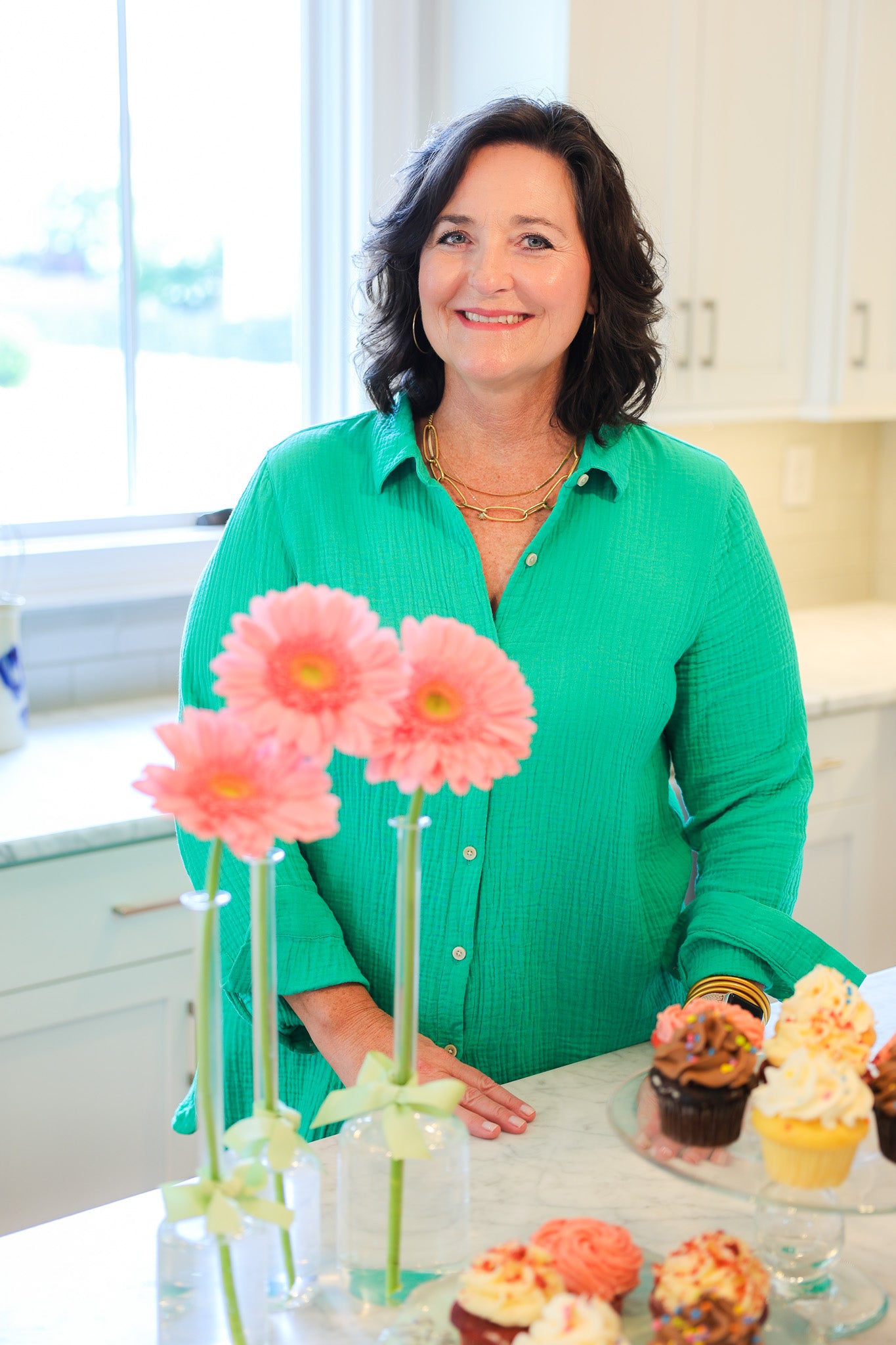 Owner of The Capstone Concierge, Charlee Rodgers in her kitchen surrounded by flowers and cupcakes