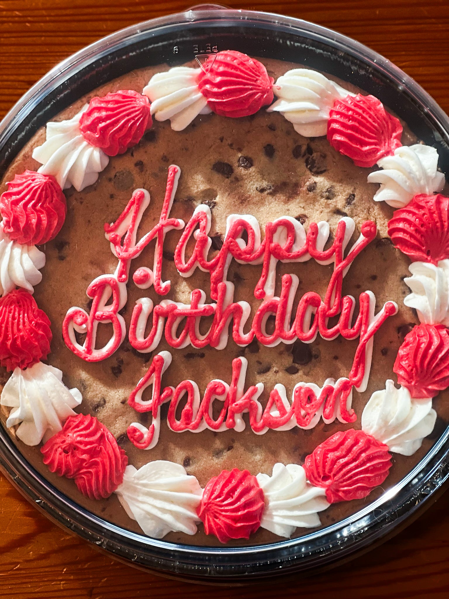 Cookie cake with red and white icing that says "happy birthday Jackson"