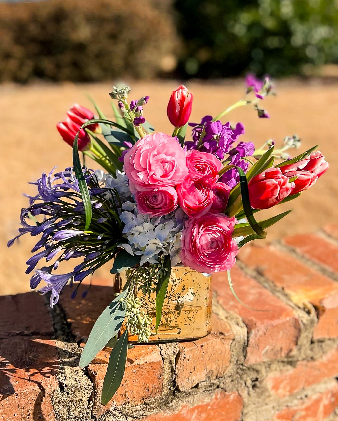 Pink and purple flower arrangement on a brick wall