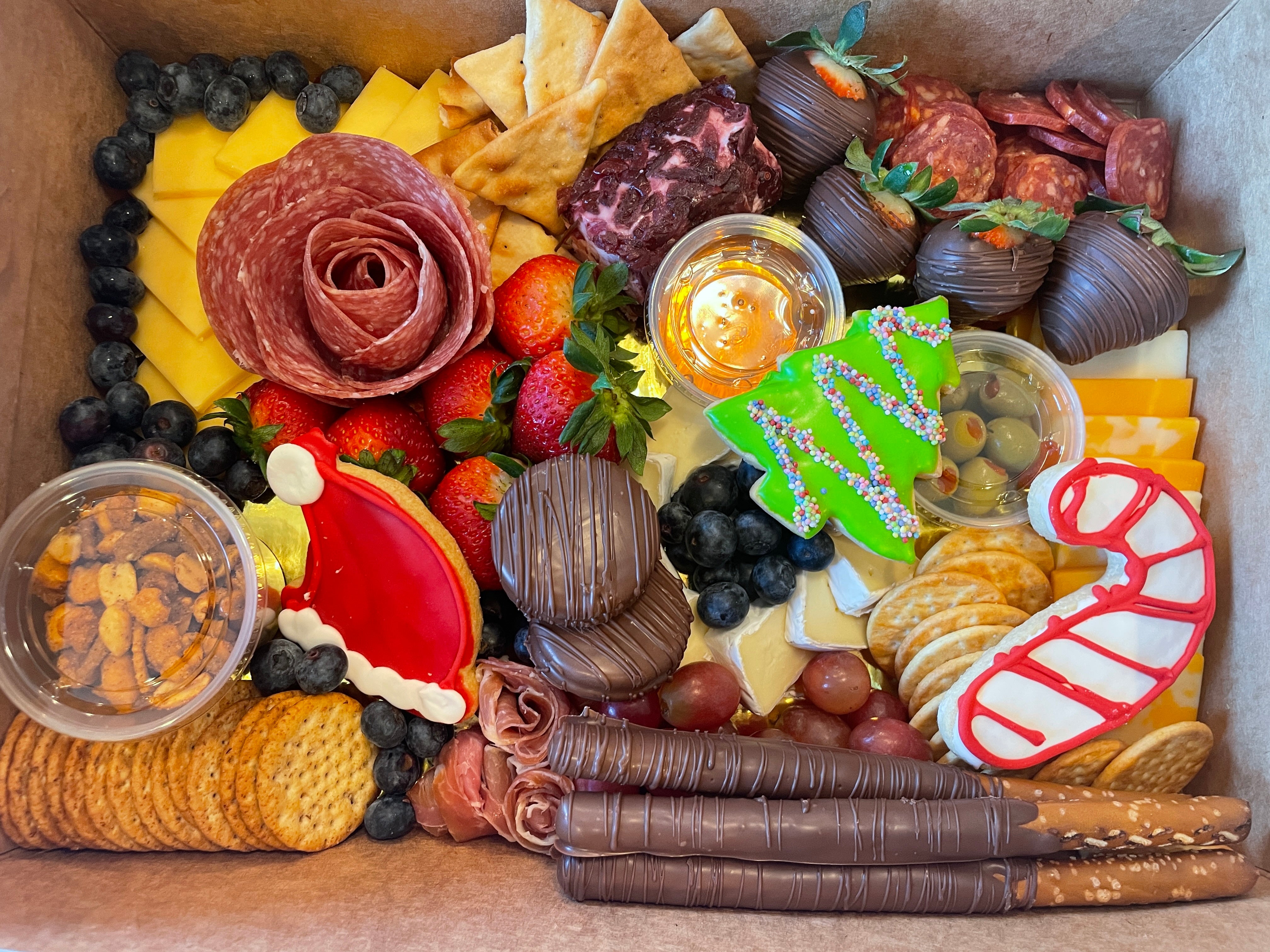 Christmas themed charcuterie board prepared for delivery in Tuscaloosa. It features cheese, fruits, Christmas cookies, meats and crackers.