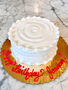 Cake with white icing on a gold platter with red writing "Happy birthday Jordan!"