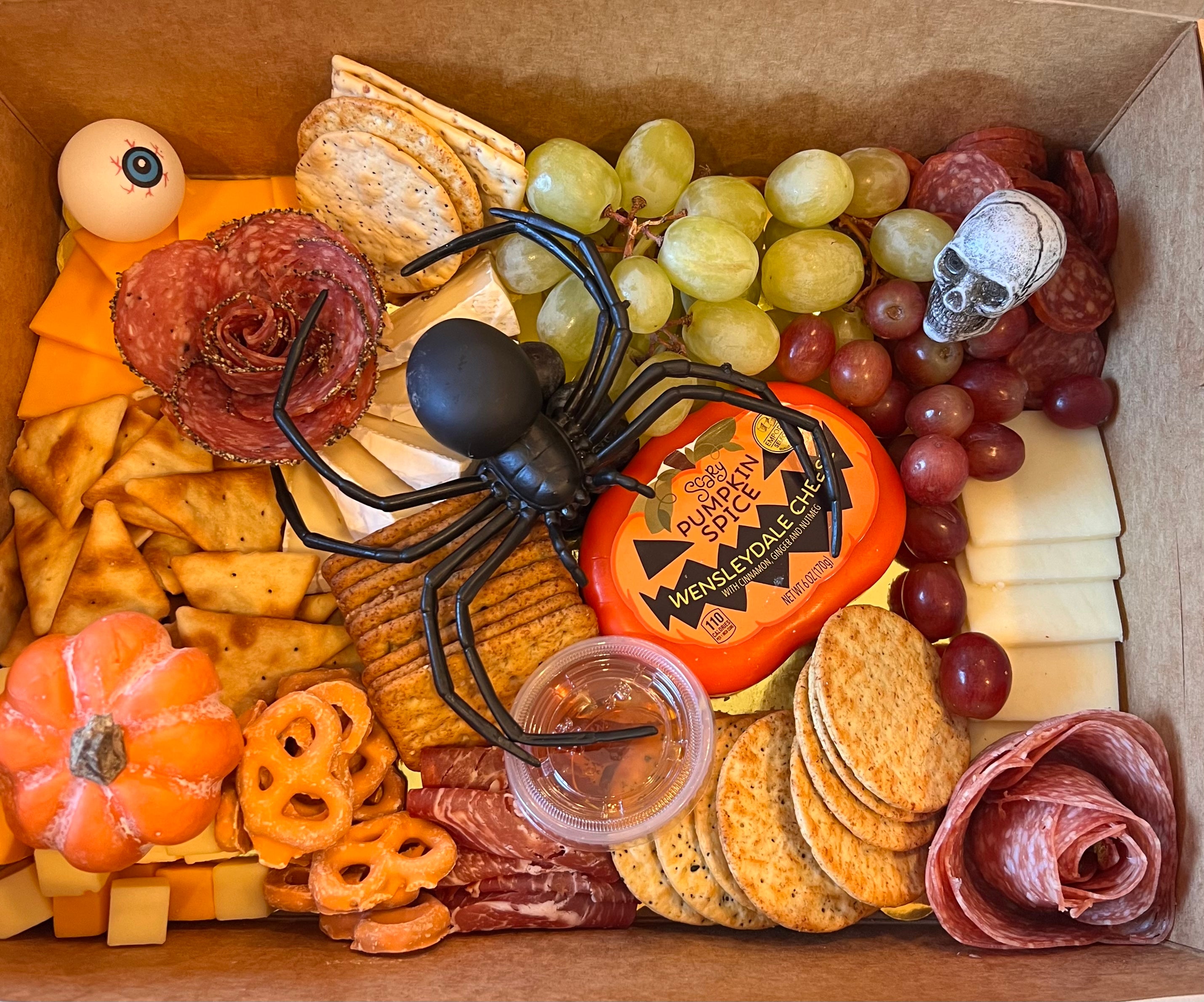 Halloween themed charcuterie board prepared for delivery in Tuscaloosa. It features crackers, cheeses, Halloween decor, meats and fruits.