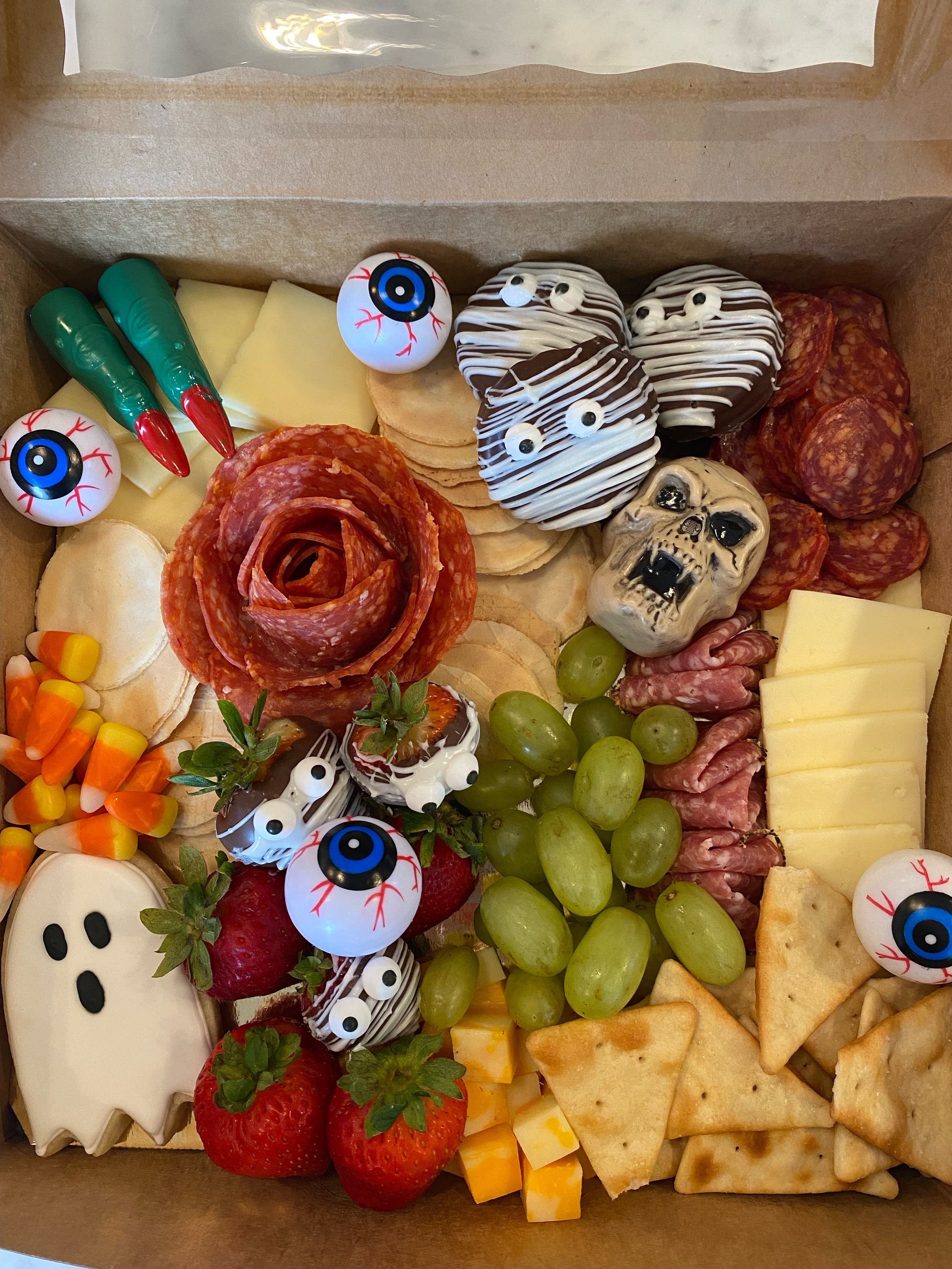 Halloween themed charcuterie board prepared for delivery in Tuscaloosa Alabama. It features crackers, meats, fruits, and candy corn and halloween treats and decor.