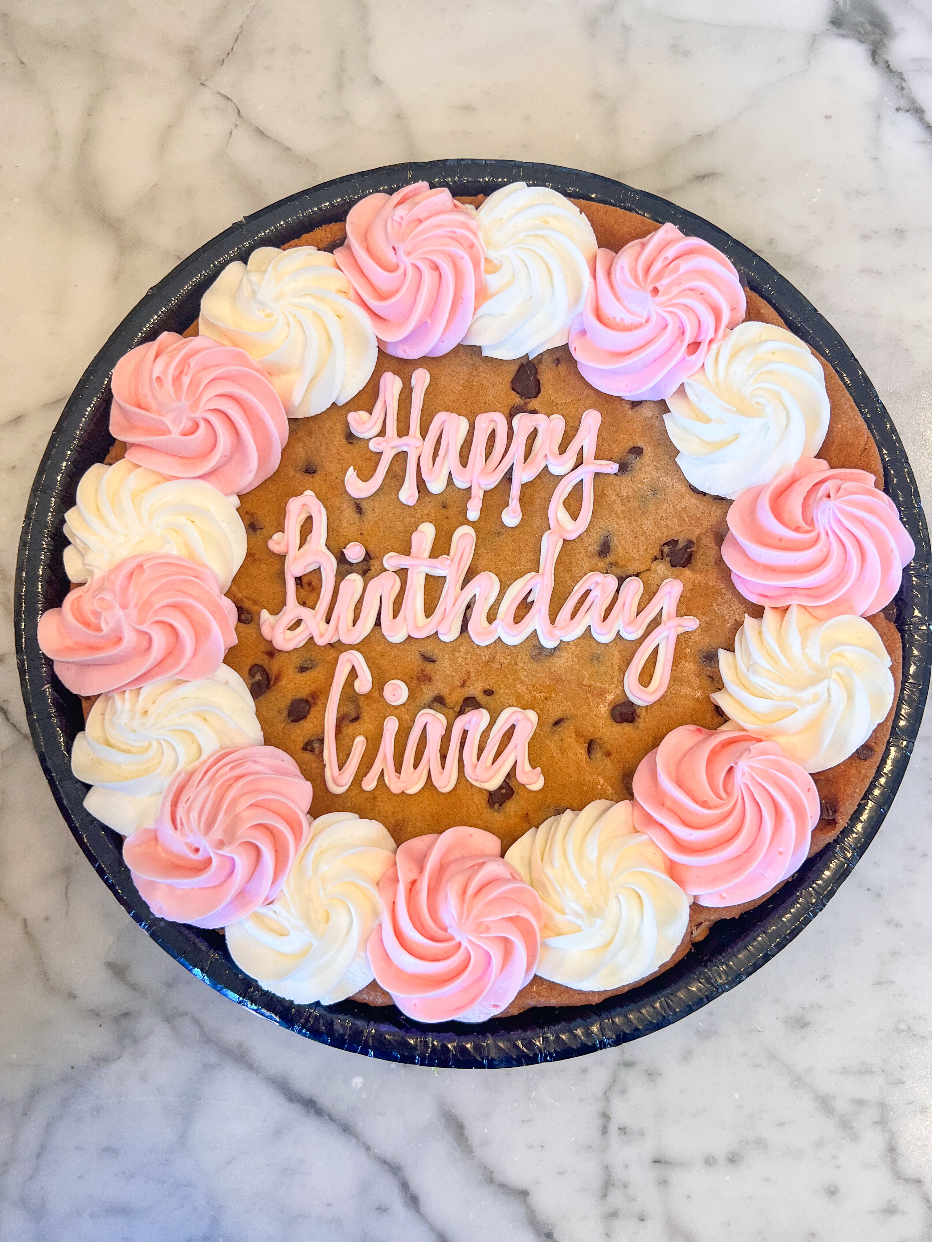 Cookie cake with white and pink icing that says "Happy birthday Ciara"