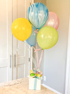 Various color balloon bundle tied to a gift box