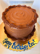 Chocolate cake on a gold platter with blue icing that says "Happy birthday Ben!"