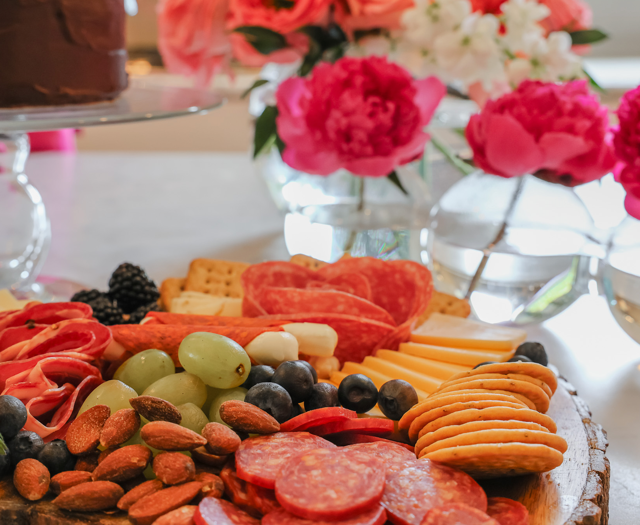 Charcuterie board with pink flowers in the background