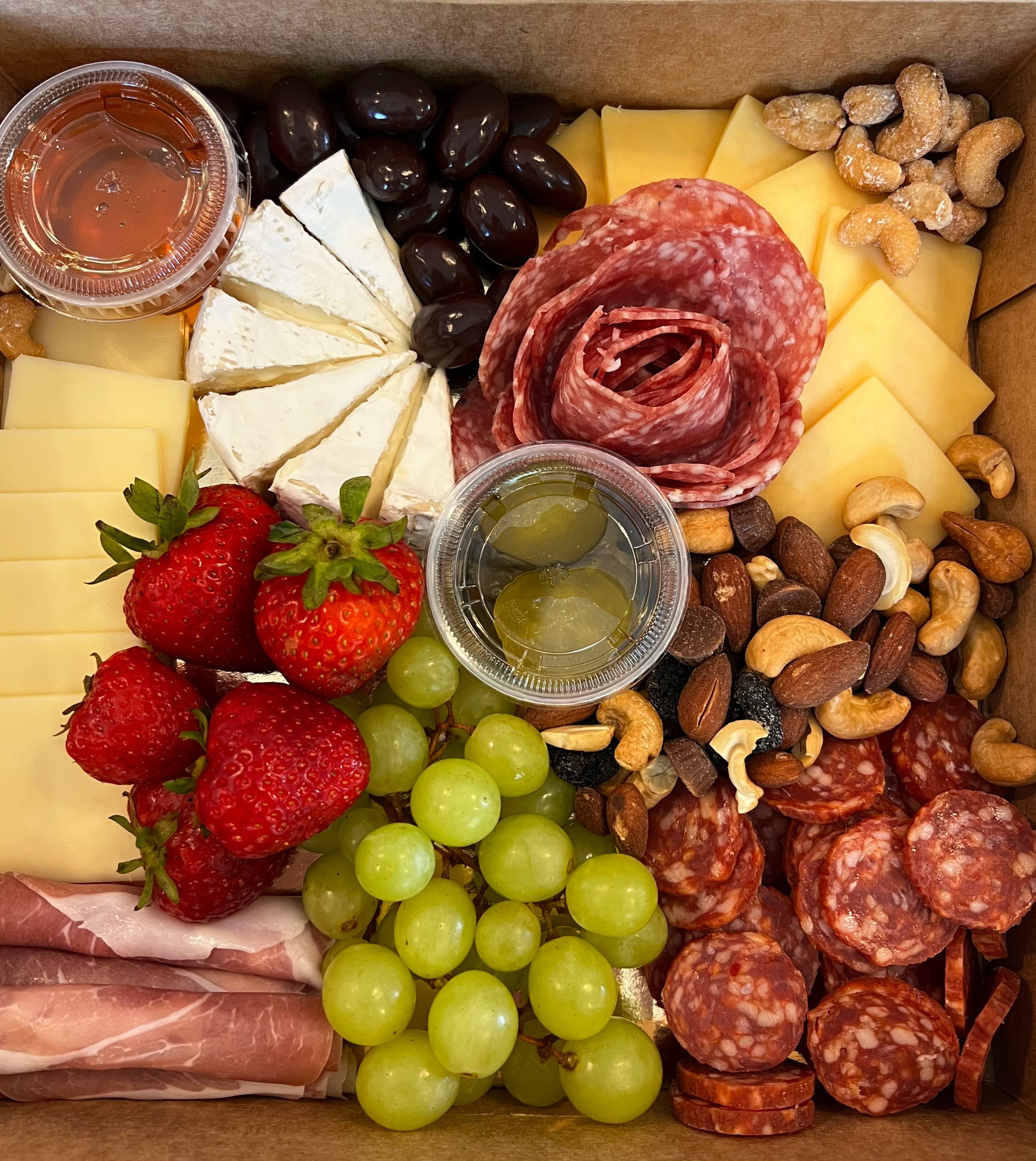 Charcuterie board prepared for delivery with cheese, nuts, meats and fruit