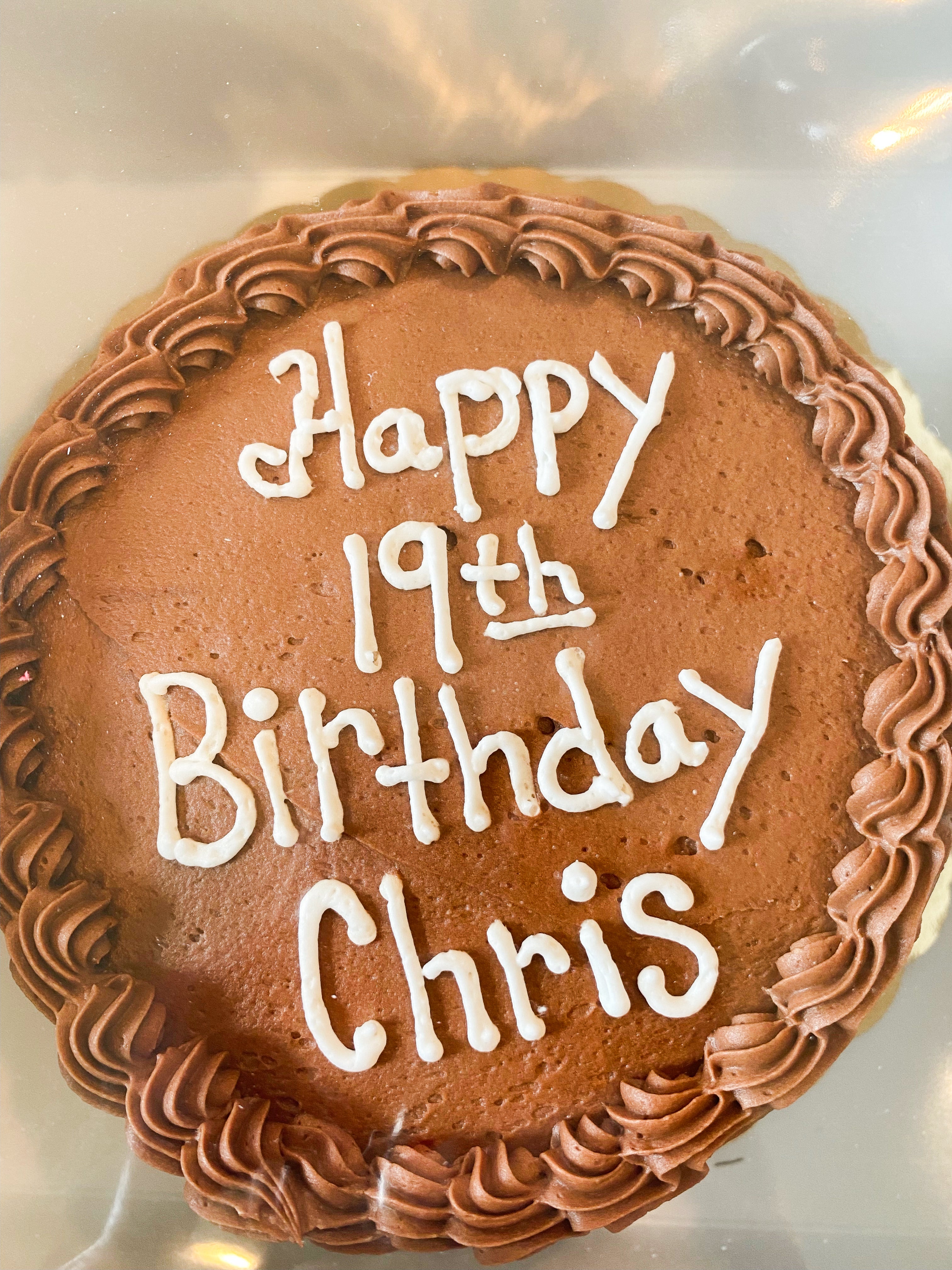 Cake with brown icing that says "happy 19th birthday Chris"